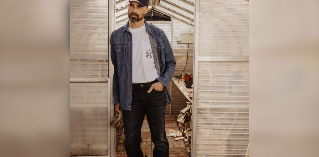 Man in workwear in front of greenhouse.