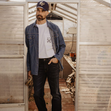 Man in workwear in front of greenhouse.
