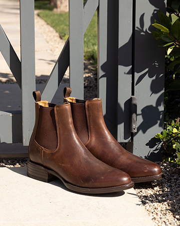 A pair of Chelsea boots with greenery.