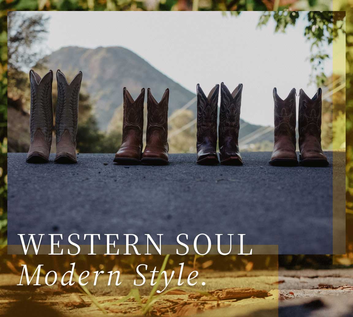 brown boots lined up on the road with hill in background